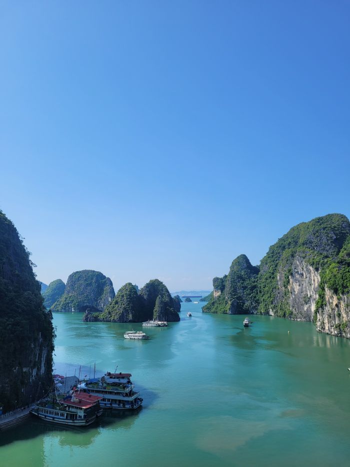 Breathtaking panorama of Ha Long Bay with limestone islands and boats under a clear blue sky.